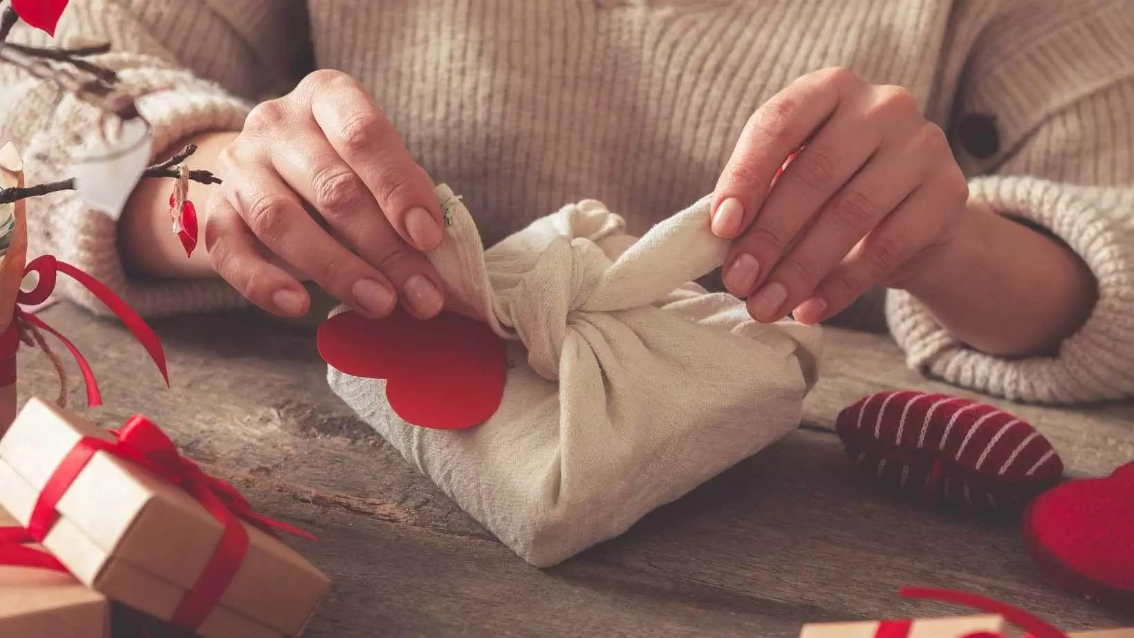 Hand wrapping gift with hearts